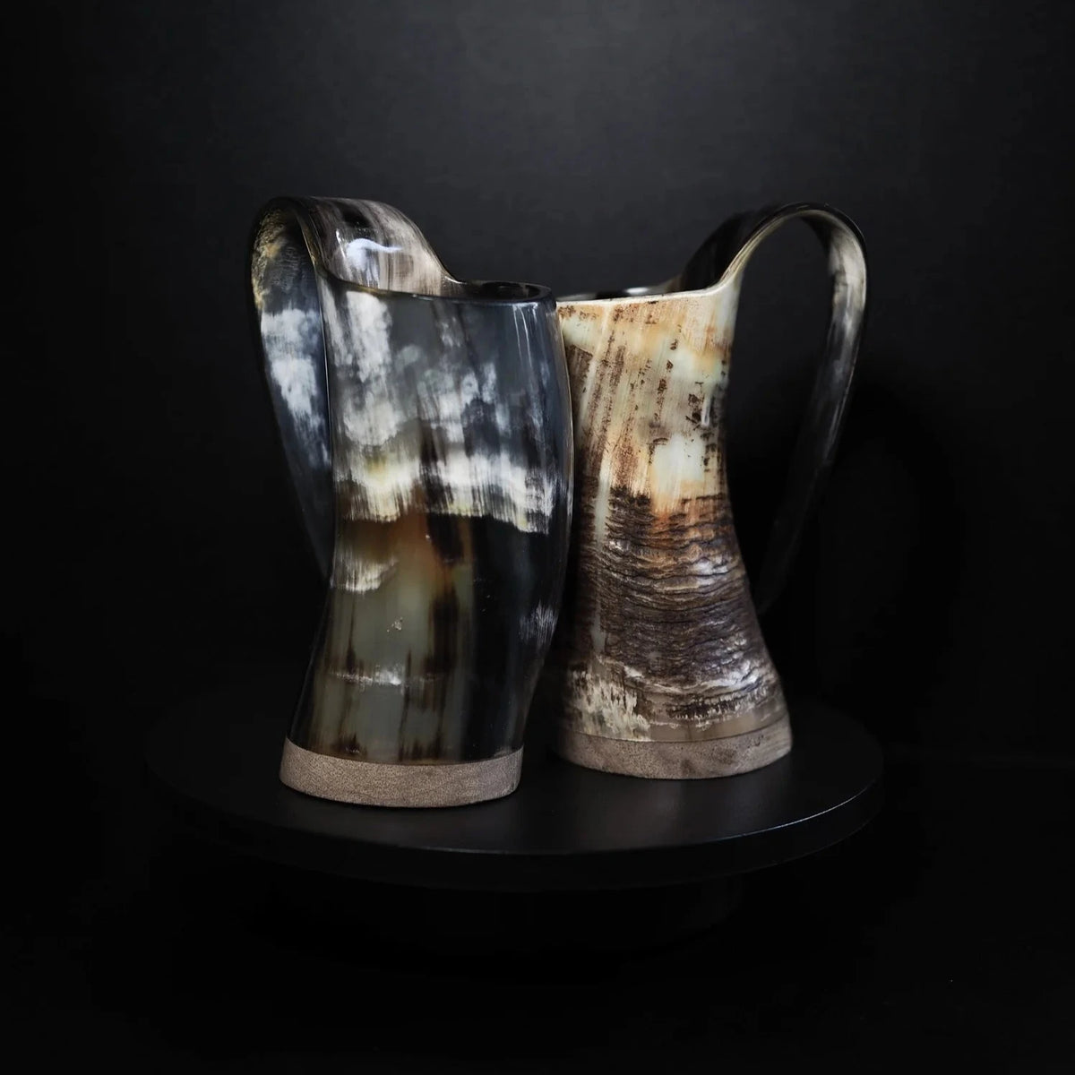 Två varianter av hornölmugg Balder 350ml, visar naturlig färgvariation i hornet från ljust till mörkt.