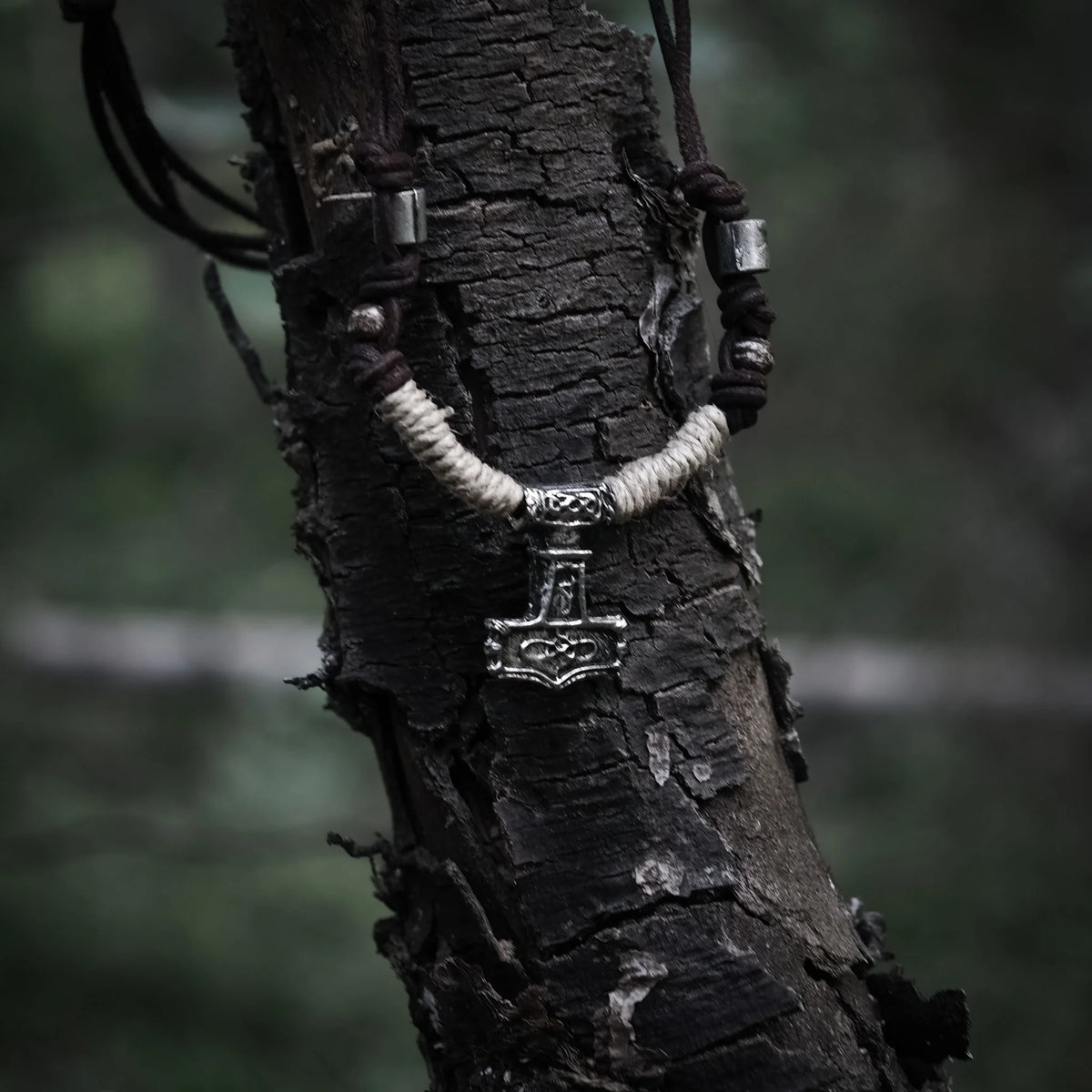 Mjölner-halsband i tenn på trädbark. Tennhammare med Viking-mönster hänger på naturligt färgat läderband med detaljer.