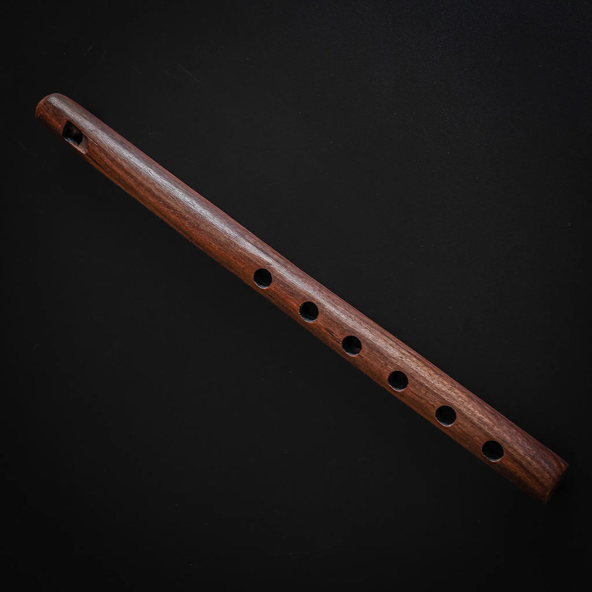 Wooden flute seen from above with blow hole and finger holes
