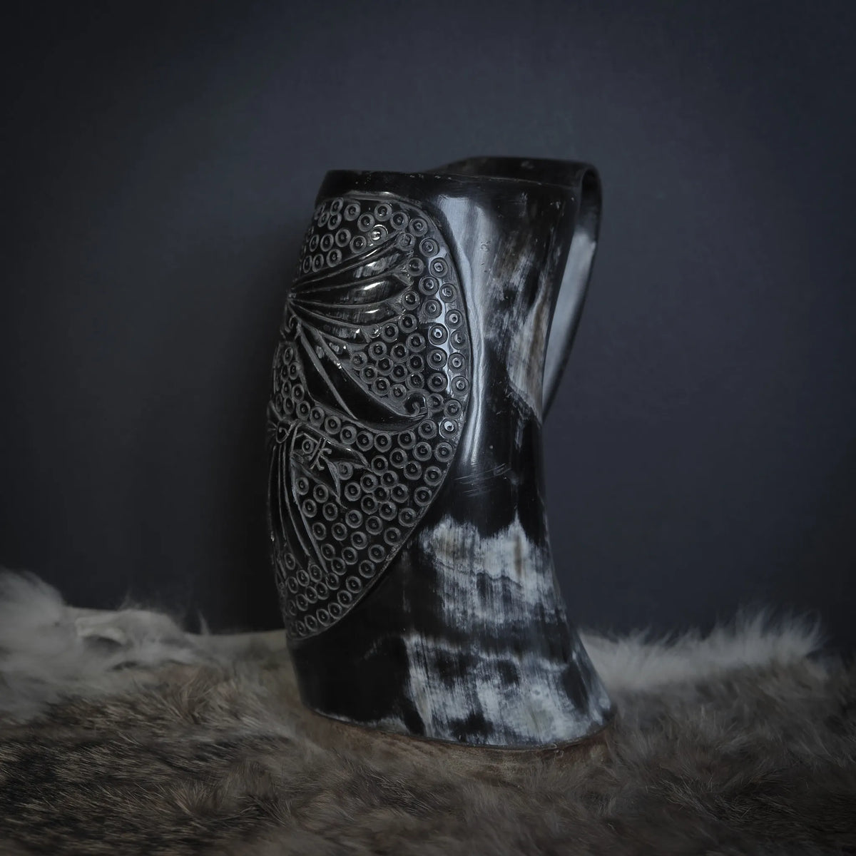 Hornmugg med dubbla körpkarv - Hugin och Munin - båda med detaljerade fjädrar framträdande. Omfattande prickad bakgrundsfyllning skapar traditionell nordisk designkänsla.