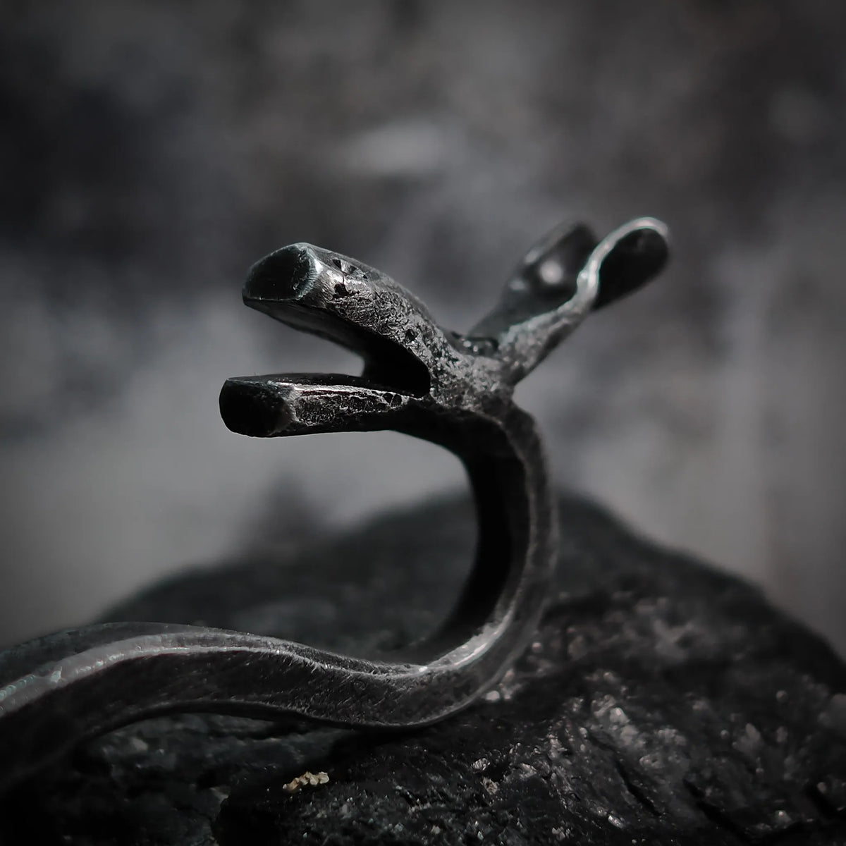 Detalj av handsmedd älgflasköppnare med synliga smedslagningsmärken på järnet