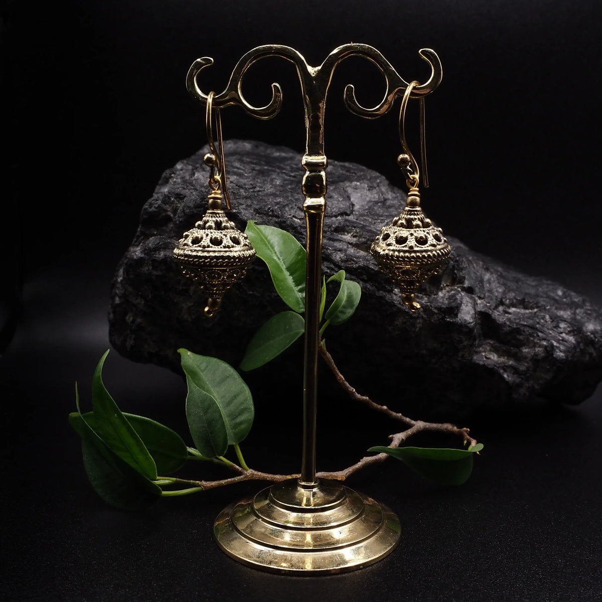 Vikingapärlor örhänge på dekorativ mässing-presentationsställ med krullad design och grona växtdetaljer