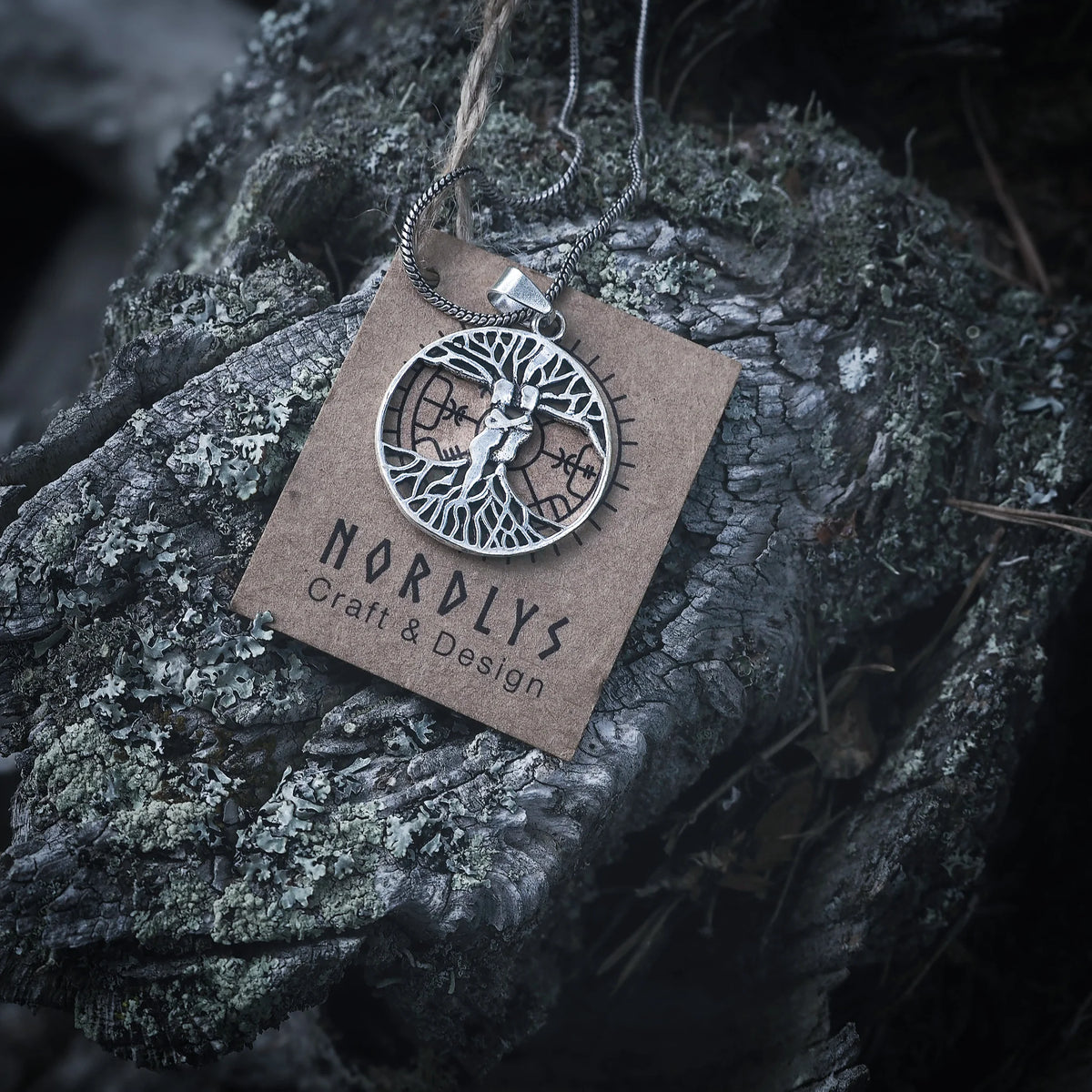 Silverfärgad rundhalsprydnad med Ask och Embla-motiv från livets träd (Yggdrasil), upphängd på ett läderband med NORDLYS-märke