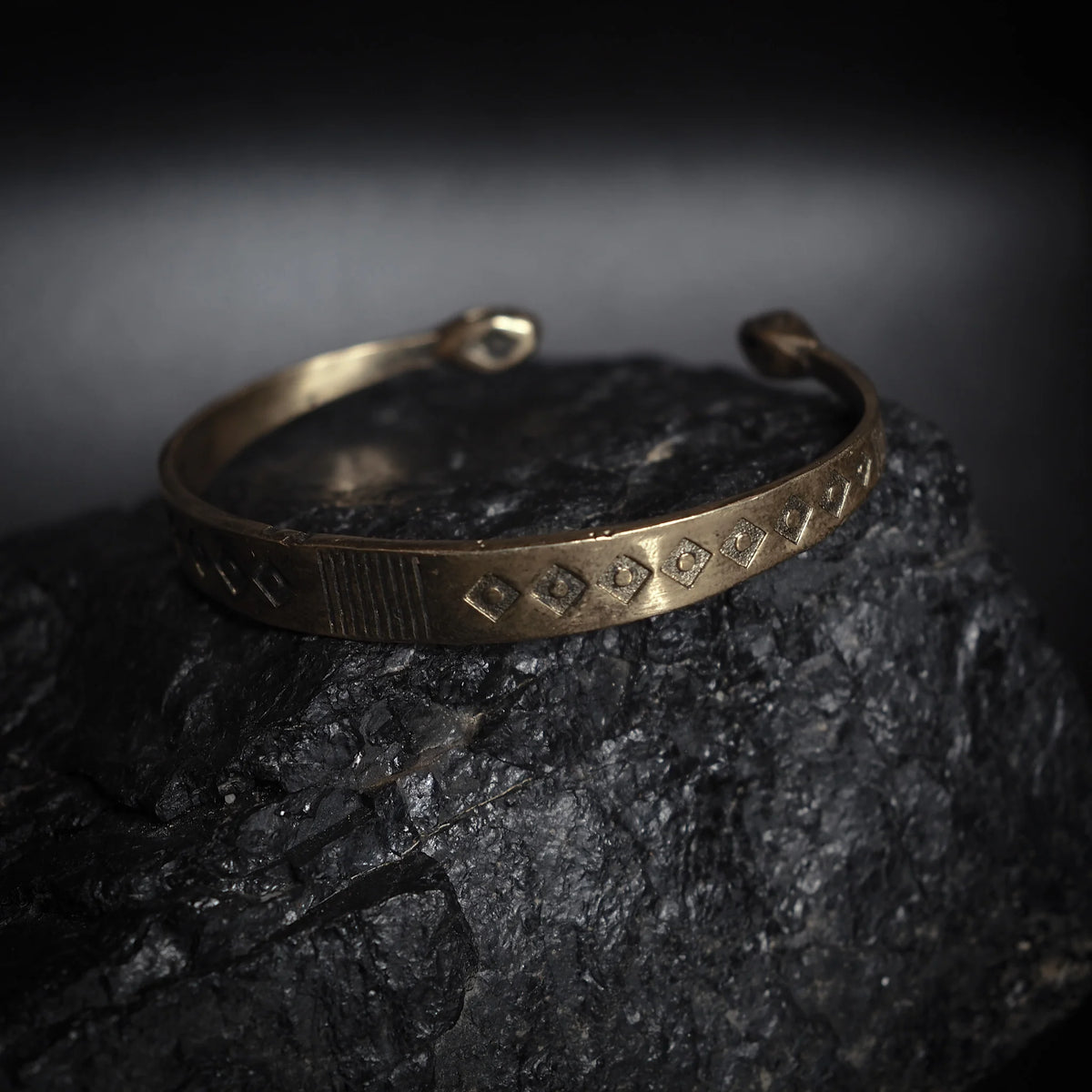 Öppet mässingsarmband med stämplat vikinginspirerad mönster av romber och geometriska linjer