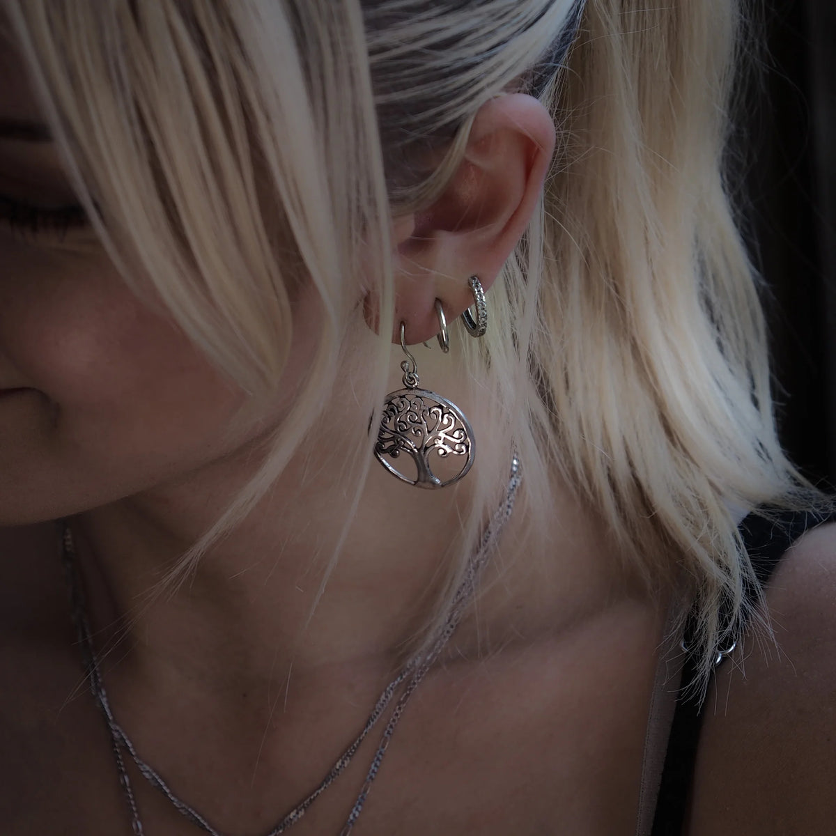 Silverfärgad Tree of Life/Yggdrasil-örhängsmycke på öra, med detaljerat träd- och rotmotiv