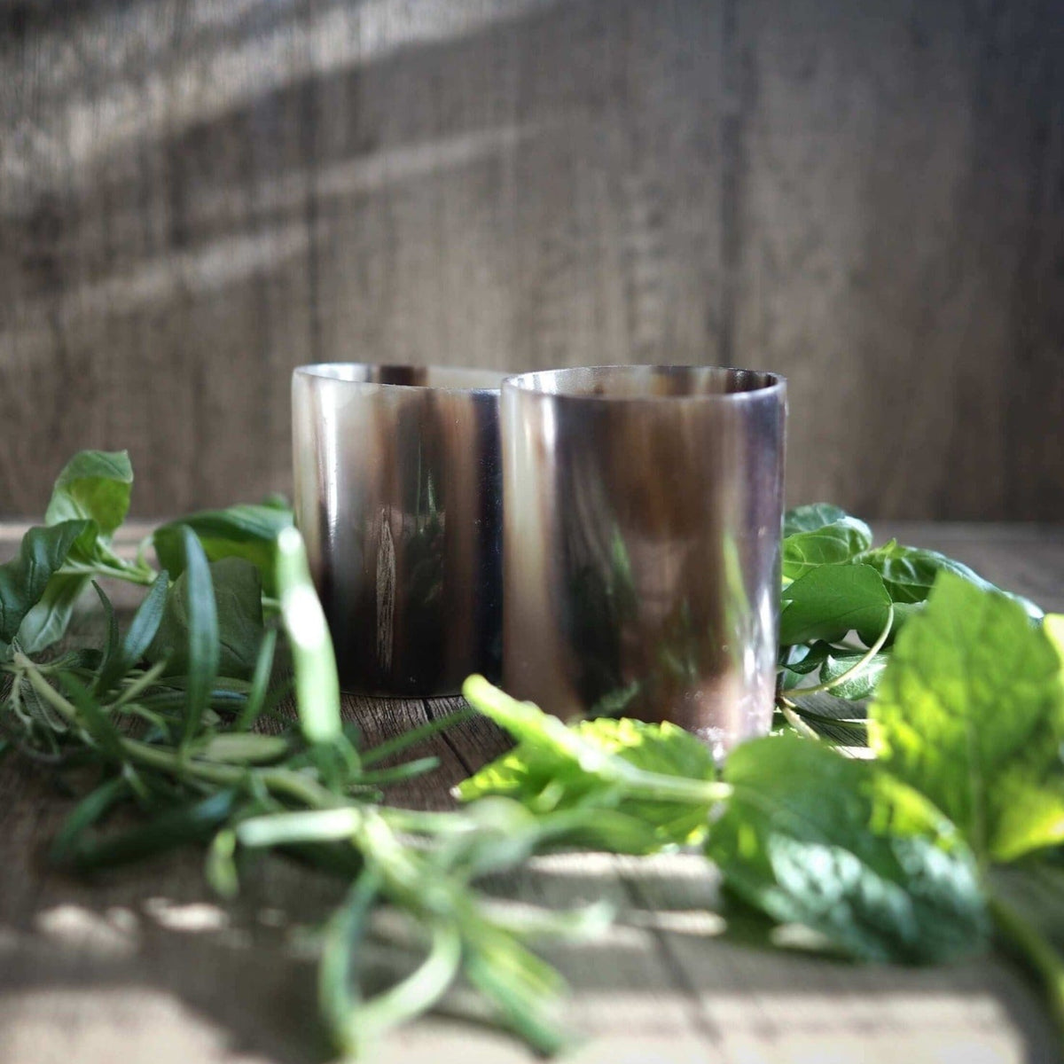 Polerade whiskysglas i horn med glatt finish på träyta, dekorerade med gröna örter