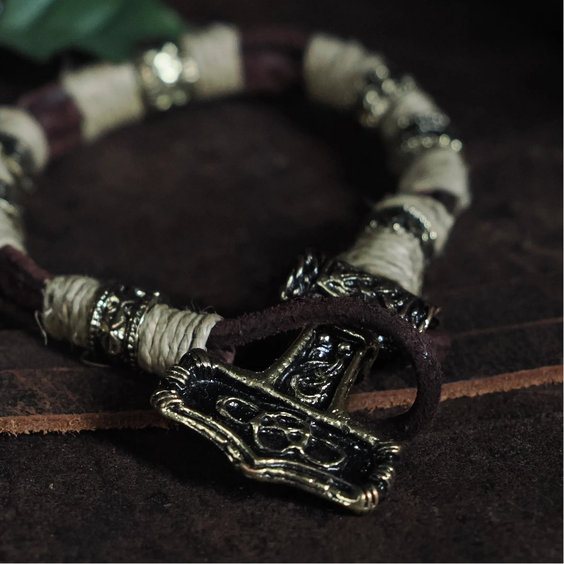 Armband med Torshammarfäste på vrist, visar mörkläder och patinerad mässing