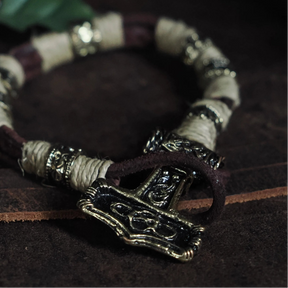 Armband med Torshammarfäste på vrist, visar mörkläder och patinerad mässing