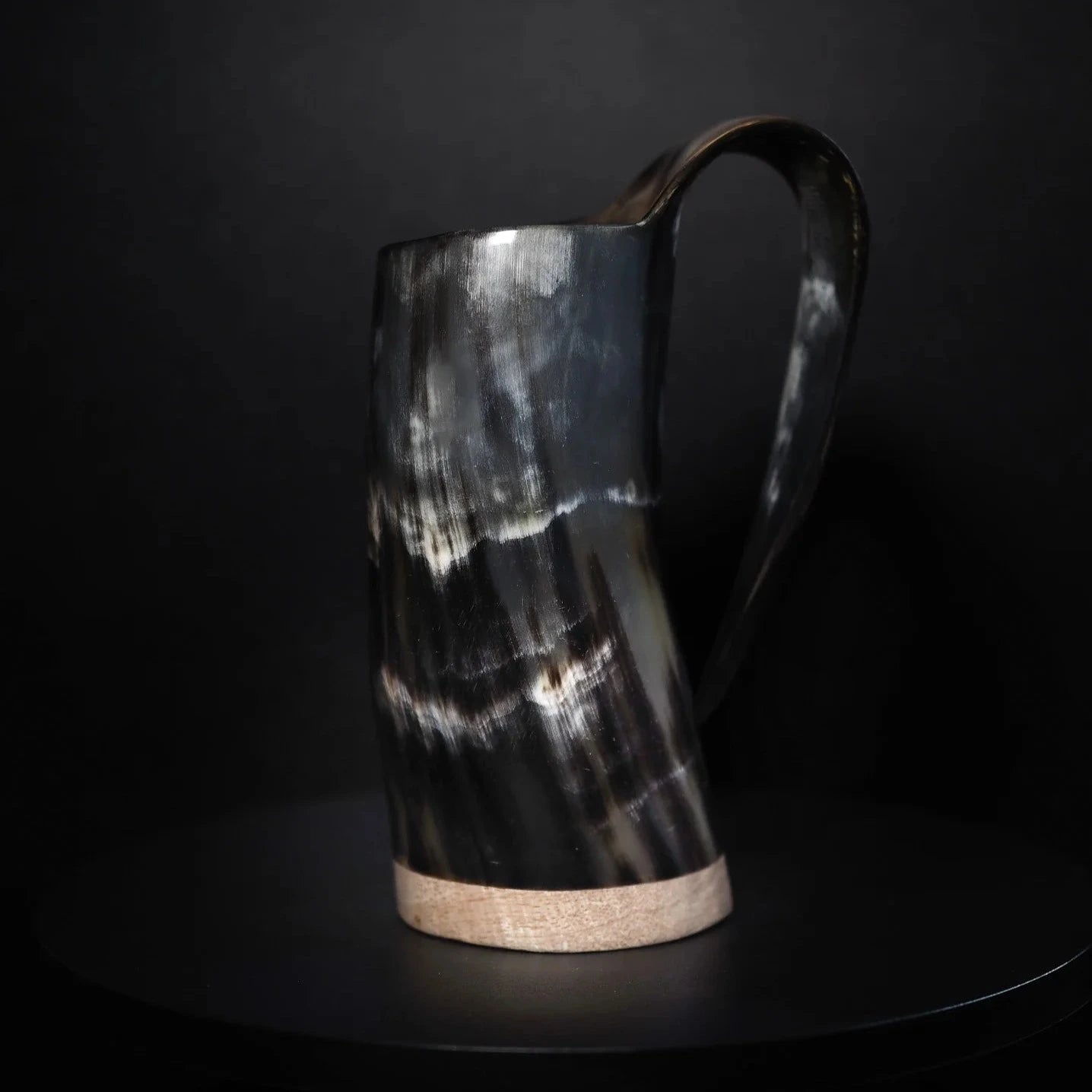 Mörk hornöl mugg med polerad yta och naturlig hornstruktur. Cylindrisk form med böjd handtag, minimalistisk design.