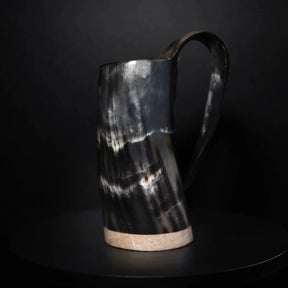 Mörk hornöl mugg med polerad yta och naturlig hornstruktur. Cylindrisk form med böjd handtag, minimalistisk design.