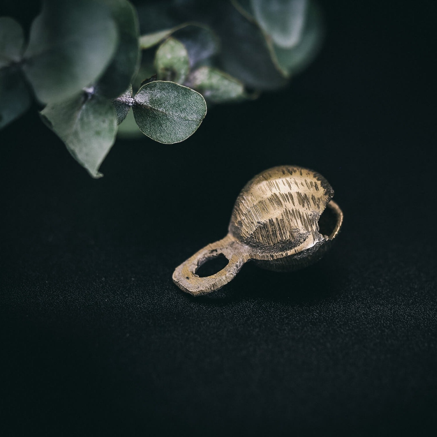 35mm mässingklocka med 'Rispig' (ripplad) yta. Linjära åsar skapar vågande reliefmönster över hela ytan. Sfärisk form med ögla för fastsättning. Naturlig belysning visar metallisk glans.