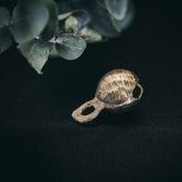 35mm mässingklocka med 'Rispig' (ripplad) yta. Linjära åsar skapar vågande reliefmönster över hela ytan. Sfärisk form med ögla för fastsättning. Naturlig belysning visar metallisk glans.