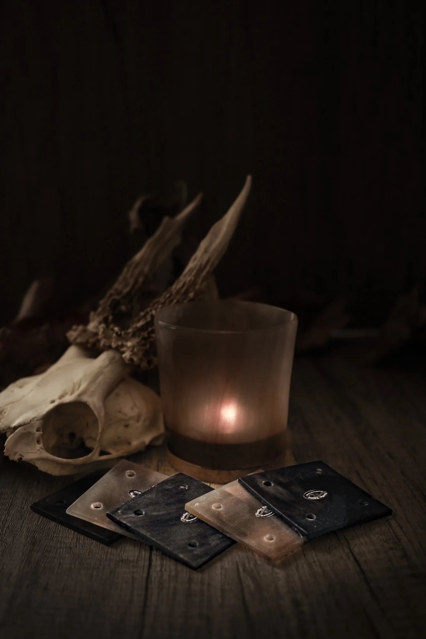 Stiliserad fotografi av hornbrickor för brickväv på mörk träbakgrund med djurkranium och eldsken i bakgrunden, framställande av traditionell vikingtidsstyling