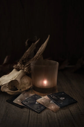 Stiliserad fotografi av hornbrickor för brickväv på mörk träbakgrund med djurkranium och eldsken i bakgrunden, framställande av traditionell vikingtidsstyling