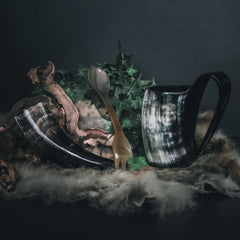 Camping-kit med två hornmugg och träkål, dekorerad med växter och moss på mörkgrön bakgrund