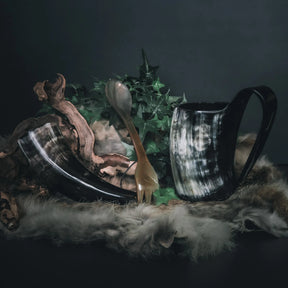 Camping-kit med två hornmugg och träkål, dekorerad med växter och moss på mörkgrön bakgrund