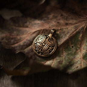 En brons evighetssymbol-hängsmycke med spiralmönster på vittrad trä, visar handgjord norsk ornamentik och antikt utseende