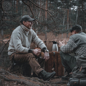 Två män i skogsmiljö, en med grå tröja håller polerad hornmugg, Nordlys logotyp synlig, höst/vinterscen