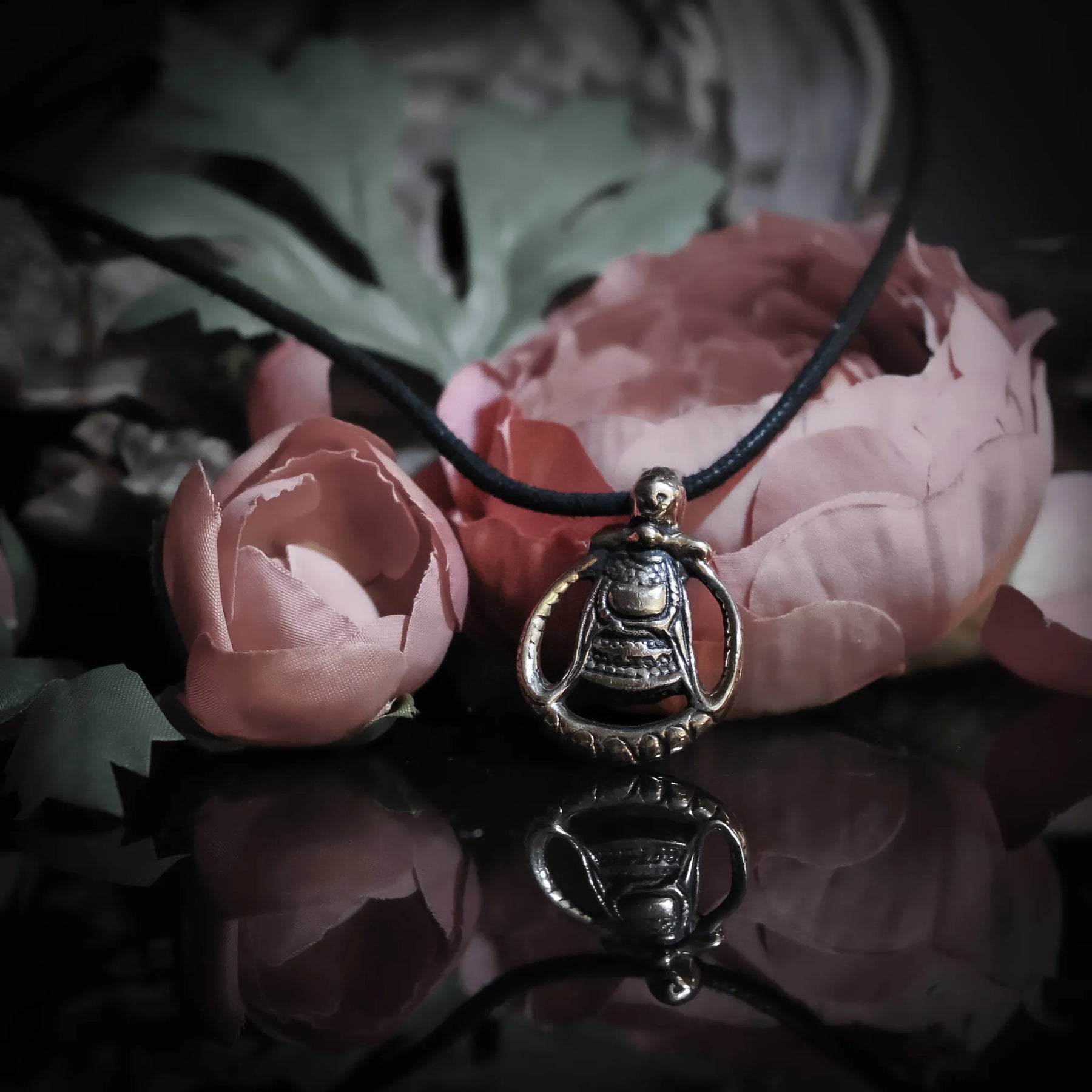 Bronsad Frejasmycke på svart läderrem, fotograferad med rosa rosor för att framhäva kärleks- och gudinnasymbolik