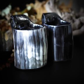 Två handgjorda glöggnuggar i horn med polerad svart yta och synlig naturlig kornstruktur, närbild.