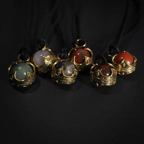 Sex Gotlandskula-hängen i mässing med halvädla stenar på svart lädersnöre, visar klassisk vikingart-smycke med ornamental design