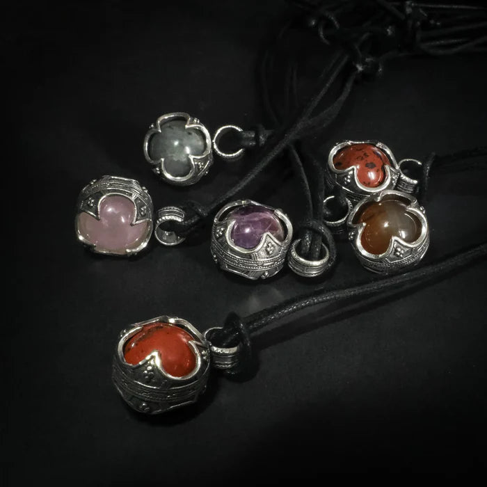 Sex Gotlandskula-hängen i silverpläterad metall med halvädla stenar som ametist, rosenkvarts och karnelsten på svart lädersnöre