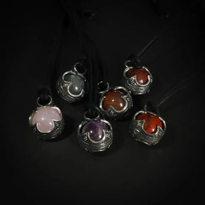 Gotlandskula-hängen i både silver och mässing med halvädla stenar, visar produktalternativen i olika metallfinisher på svart lädersnöre