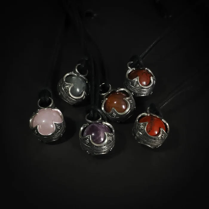 Gotlandskula-hängen i både silver och mässing med halvädla stenar, visar produktalternativen i olika metallfinisher på svart lädersnöre