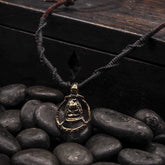 Halsband gudinnan Freja med mässingsamulett föreställande ett bi inom cirkel, på mörk läderrem, dramatisk närbild.