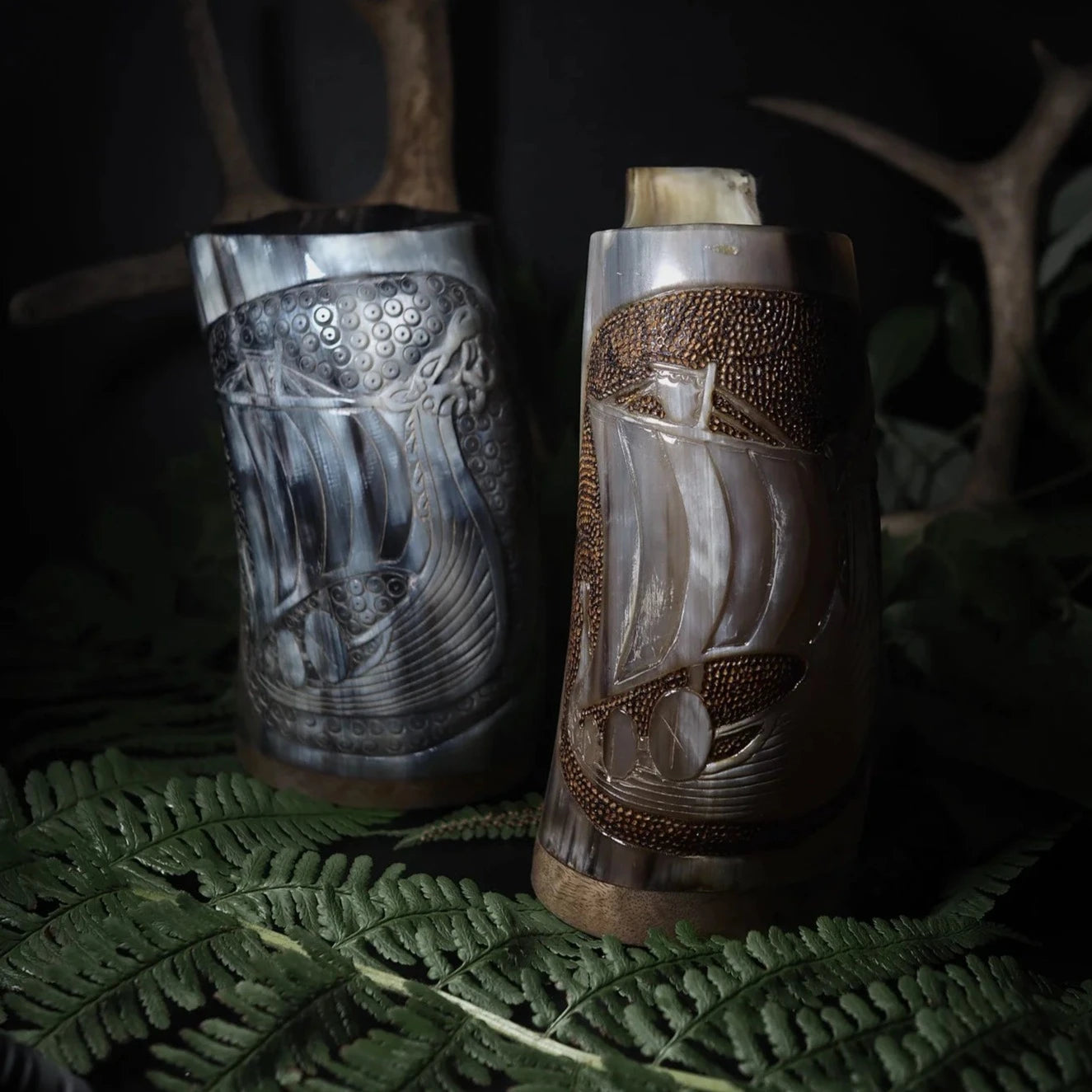 Handsnidad hornmugg med vikingskepp-motiv, visar traditionell utskärning av ett långskeppsdesign med naturlig horn i beige och bruna toner.