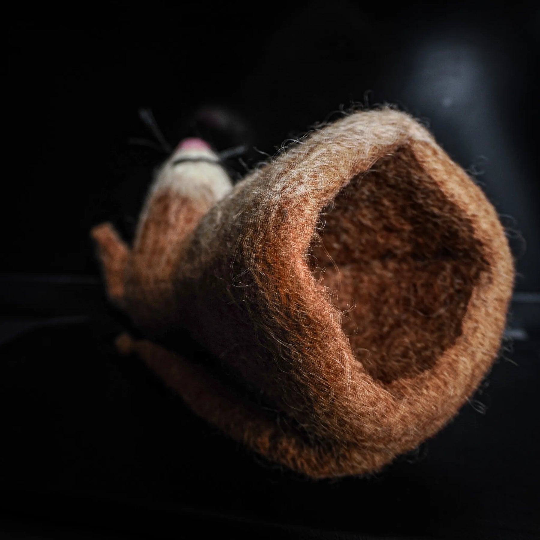 Närbild av handfiltsad ulläggvärmare med mörkbrun och beige fiber
