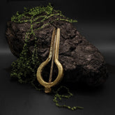 Jaw harp traditional tuned variant in brass with gold-bronze sheen on natural stony environment