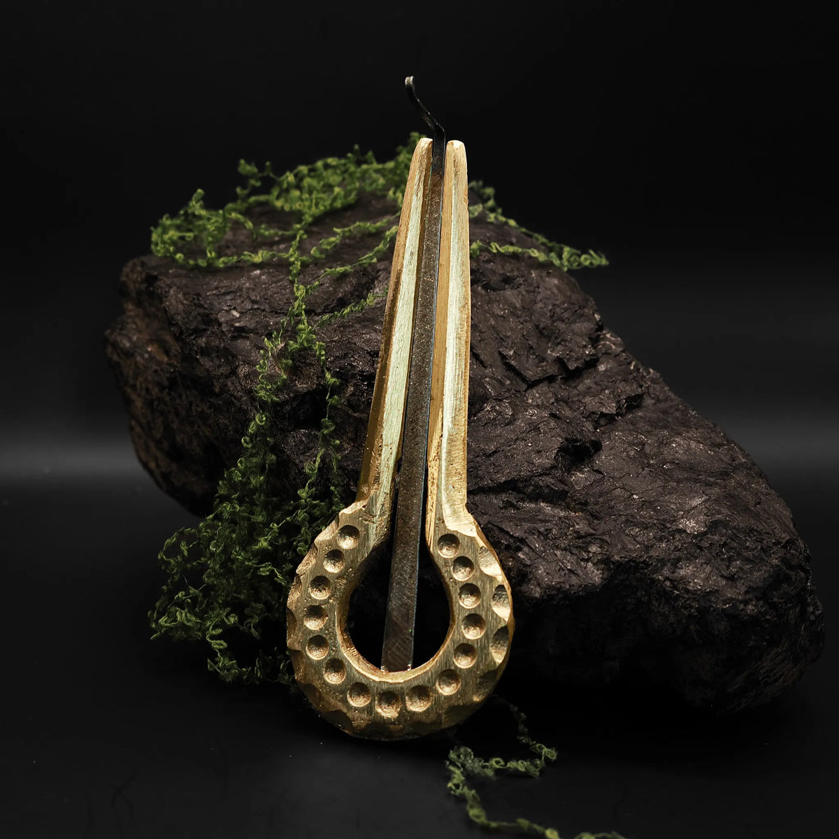 Mungiga med låda - Stämd i mässing med dekorativt perforerat resonanshålrum, vibrande metallstöd och läderband, fotograferad mot mossväxt sten och skogsscen