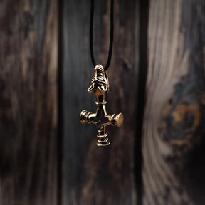 Bronze Vargkors (wolf cross) Viking pendant hanging from black waxed cord against wood background