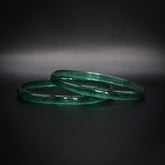 Par gröna glasarmband med genomskinlig struktur, vikingatida reproduktion mot mörk bakgrund