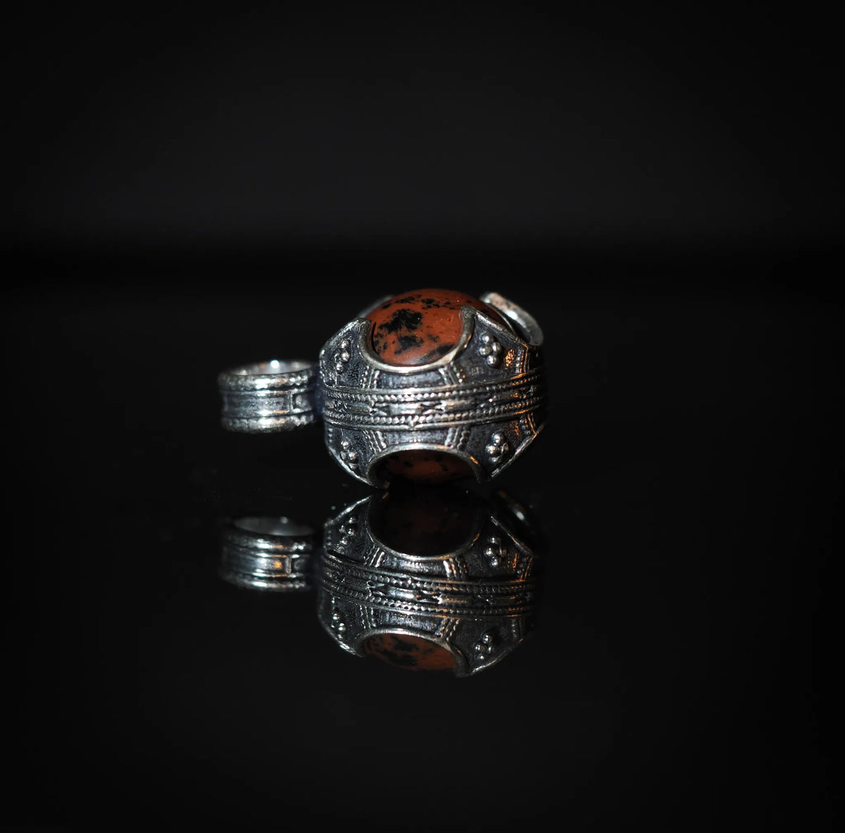 Gotlandshänge med mahogny obsidian i silverpläterad metallfasning, fotograferad från sidan för att visa formens skulpturala detaljer.