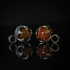 Två silverpläterade och två mässingspläterade Gotlandshängen med rödagat-stenar. Symmetrisk jämförande display av varianterna i klassisk vikingastil. Små sling-ringar bredvid varje par.
