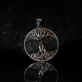 Stor träd-amulett på silverkedja fotograferad mot svart bakgrund med reflektion, visar Yggdrasil med fina detaljer i grenar och rötter.