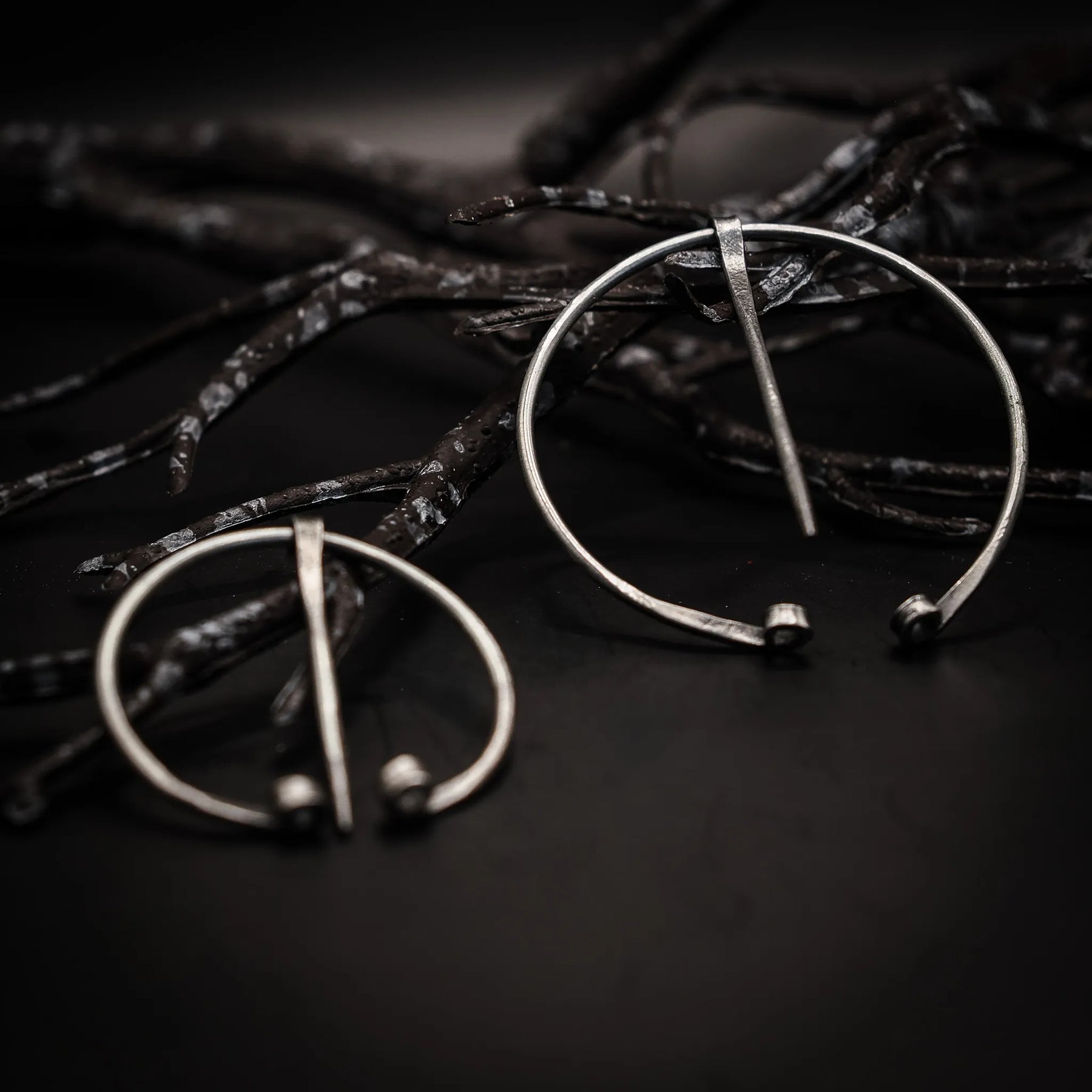 Två stålringnålar med polerad finish på mörk textil