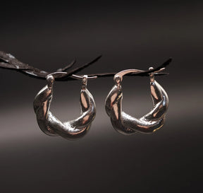 Par silverpläterade mässingsörhängen med flätmönster, ungefär 2cm