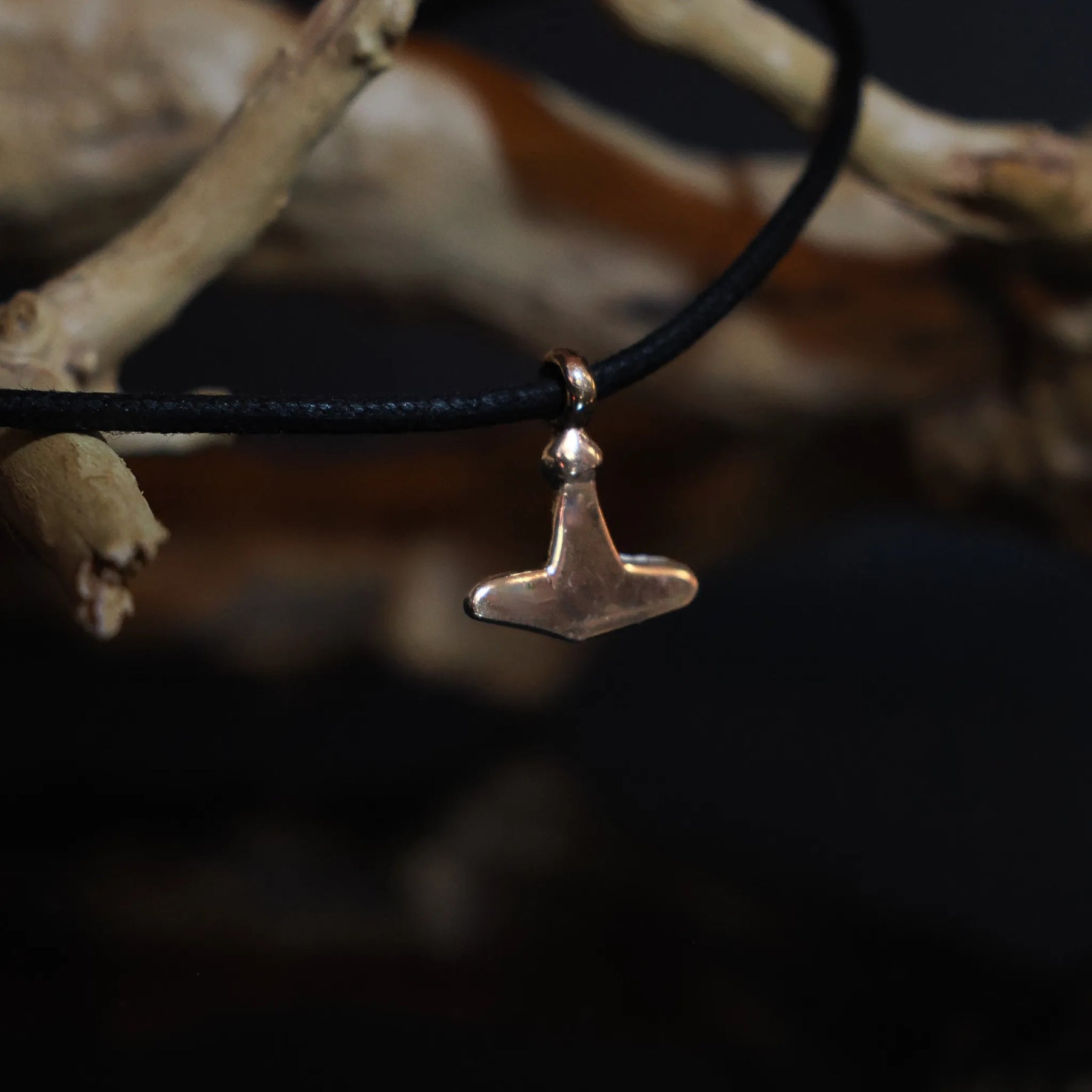 Smallest Torshammare (Thor's hammer) pendant in bronze held in human hand to show scale (1.7x1.5cm), minimal geometric form characteristic of Gotland Viking finds