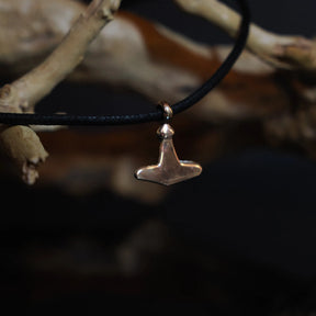 Smallest Torshammare (Thor's hammer) pendant in bronze held in human hand to show scale (1.7x1.5cm), minimal geometric form characteristic of Gotland Viking finds