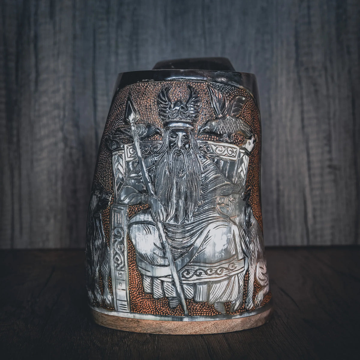 Handsnidad hornmugg med detaljerad gravering av Allfather Odin. Mugen visar en skäggig nordisk gud med hornad hjälm och ornamenterad rustning. Mässingsband vid botten. Naturlig hornfärg med ljusare kornstruktur. Tjockt, polererat horn med handformad handtag.