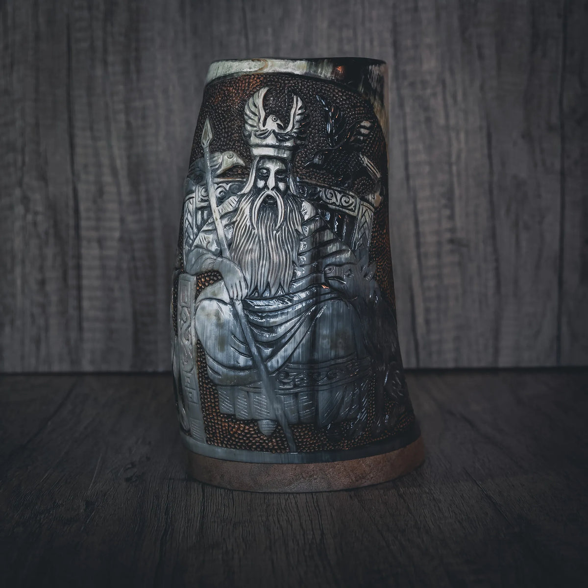 Handsnidad hornmugg med detaljerad gravering av Allfather Odin. Visar skäggig nordisk krigarfigur med hornad krona och rustningsdetaljer. Mässingsband skapar metallic accent. Djup engraving med fin linjearbete och naturligt hornmaterial.