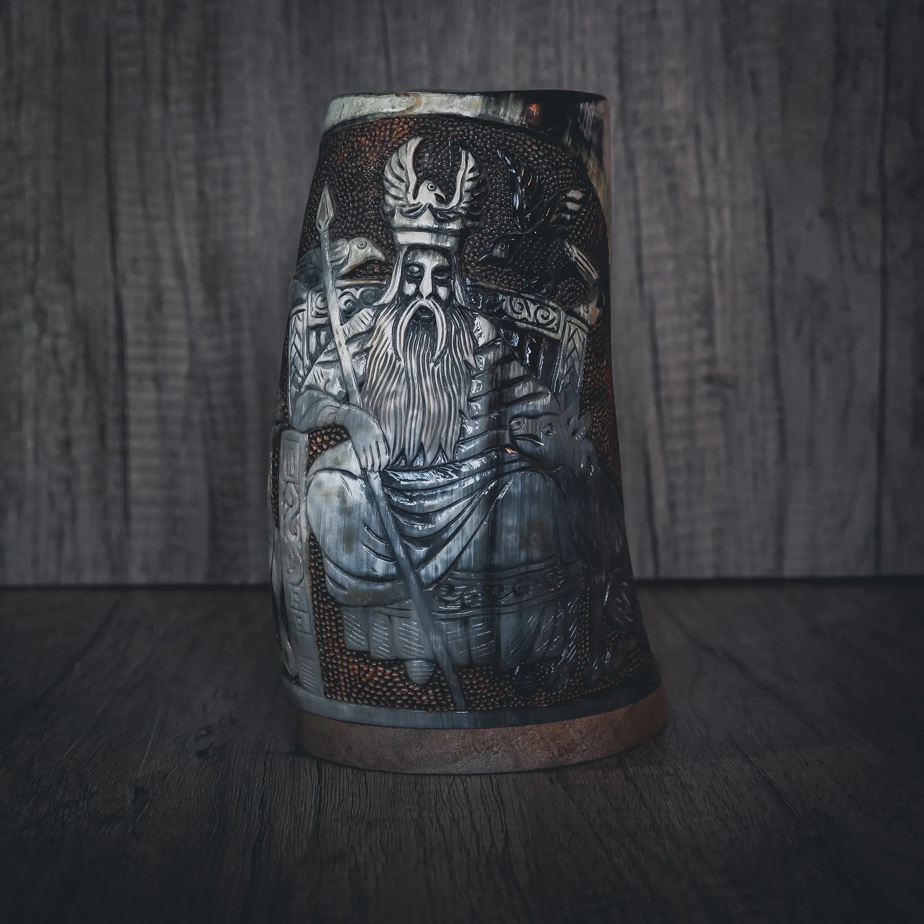 Handsnidad hornmugg med detaljerad gravering av Allfather Odin. Visar skäggig nordisk krigarfigur med hornad krona och rustningsdetaljer. Mässingsband skapar metallic accent. Djup engraving med fin linjearbete och naturligt hornmaterial.