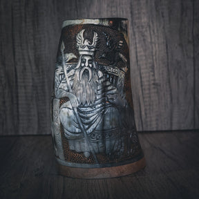 Handsnidad hornmugg med frontvy av Odin-ansikt i högt relief. Skäggig krigarfigur bär antilophornkrona. Intrikat geometriskt mönsterarbete i nordisk stil fyller ytan omkring huvudfiguren. Naturligt horn med stark färgkontrast mellan graverad och polerad yta. Kopparband vid basen. Museistandard snidning med exceptionell detalj.