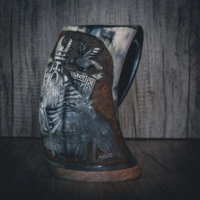 Handsnidad hornmugg med detaljerad reliefsnidning av skäggig manlig figur föreställande Allfader Oden. Texturerad yta med kraftiga mönster och gravyrer. Naturligt horn med varierande färgton. Kopparband runt basen. Professionellt produktfoto med kontrollerad belysning.