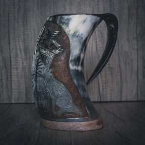 Sidovy av handsnidad hornmugg med Allfader Odens relief-gravering. Visar profilen av den skäggiga nordiska guerrafiguren. Mässingsband vid basen och handformad handtag. Naturligt hornmaterial med ljusare translucentområden.