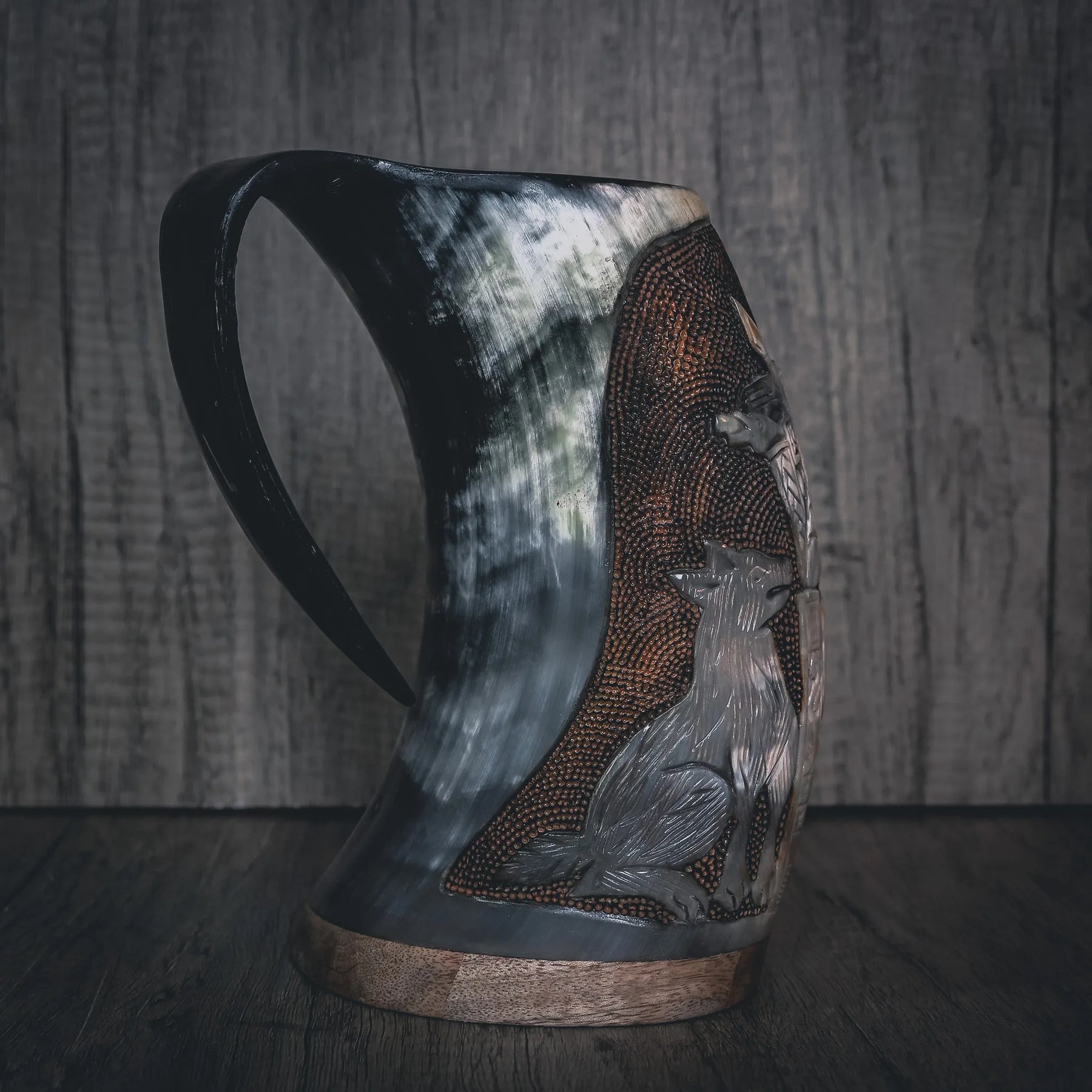 Tre-fjärdedelvy av handsnidad hornmugg med Allfader Odens graverade porträtt. Visar skäggig krigarfigur med hornad hjälm och ornamenterad bröstharnask. Handformad handtag och mässingsband vid basen. Tjockt, naturligt hornmaterial med kornstruktur.