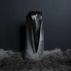 Närbildsfoto av hornmuggens kant och öppning, visar detaljerna av handsnidningen, prickiga mönstren och messingbandet runt kanten.